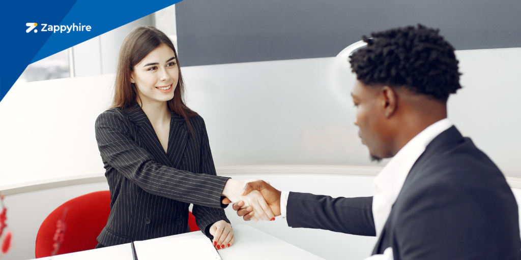 A Caucasian hiring manager is finishing up an interview with a Black male candidate.